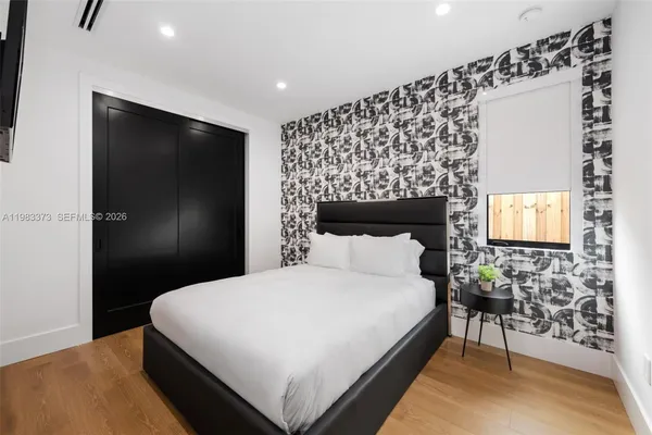 a bedroom with a bed and a flat tv screen on the dresser