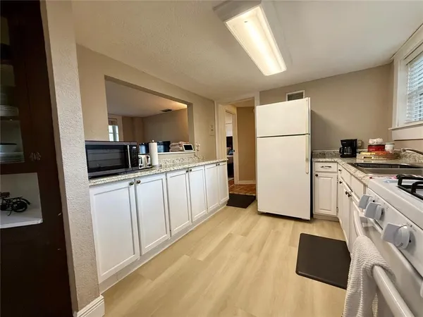 a kitchen with a refrigerator a stove top oven and white cabinets