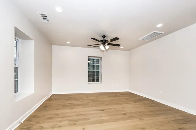 a view of empty room with wooden floor and fan
