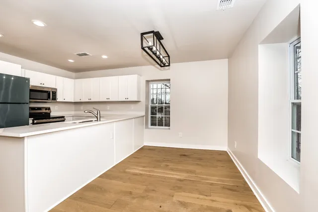 a kitchen with a refrigerator a stove top oven a counter space and cabinets