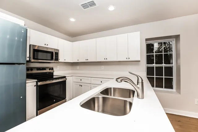 a kitchen with granite countertop a sink stainless steel appliances and cabinets