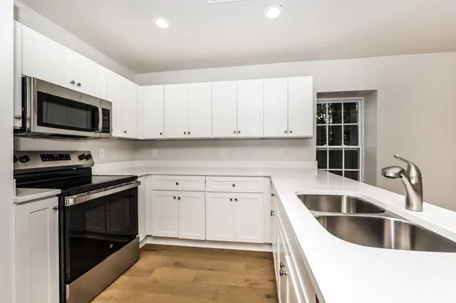 a kitchen with granite countertop a stove sink and microwave