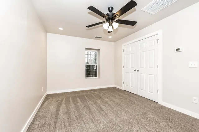 an empty room with a ceiling fan and windows