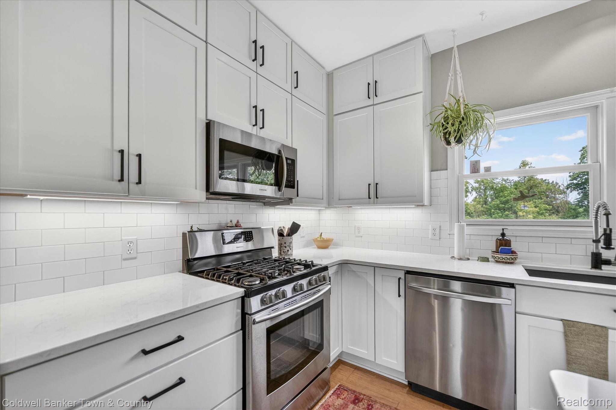 918 Gray Fox Court Howell, MI 48843 - Photo 12 of 84 Modern kitchen featuring white shaker cabinetry, stainless steel appliances, white subway tile backsplash, and light-toned countertops