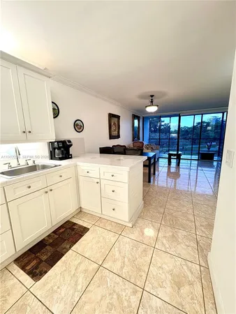 a kitchen with stainless steel appliances a stove a sink a counter top space cabinets and a view of living room