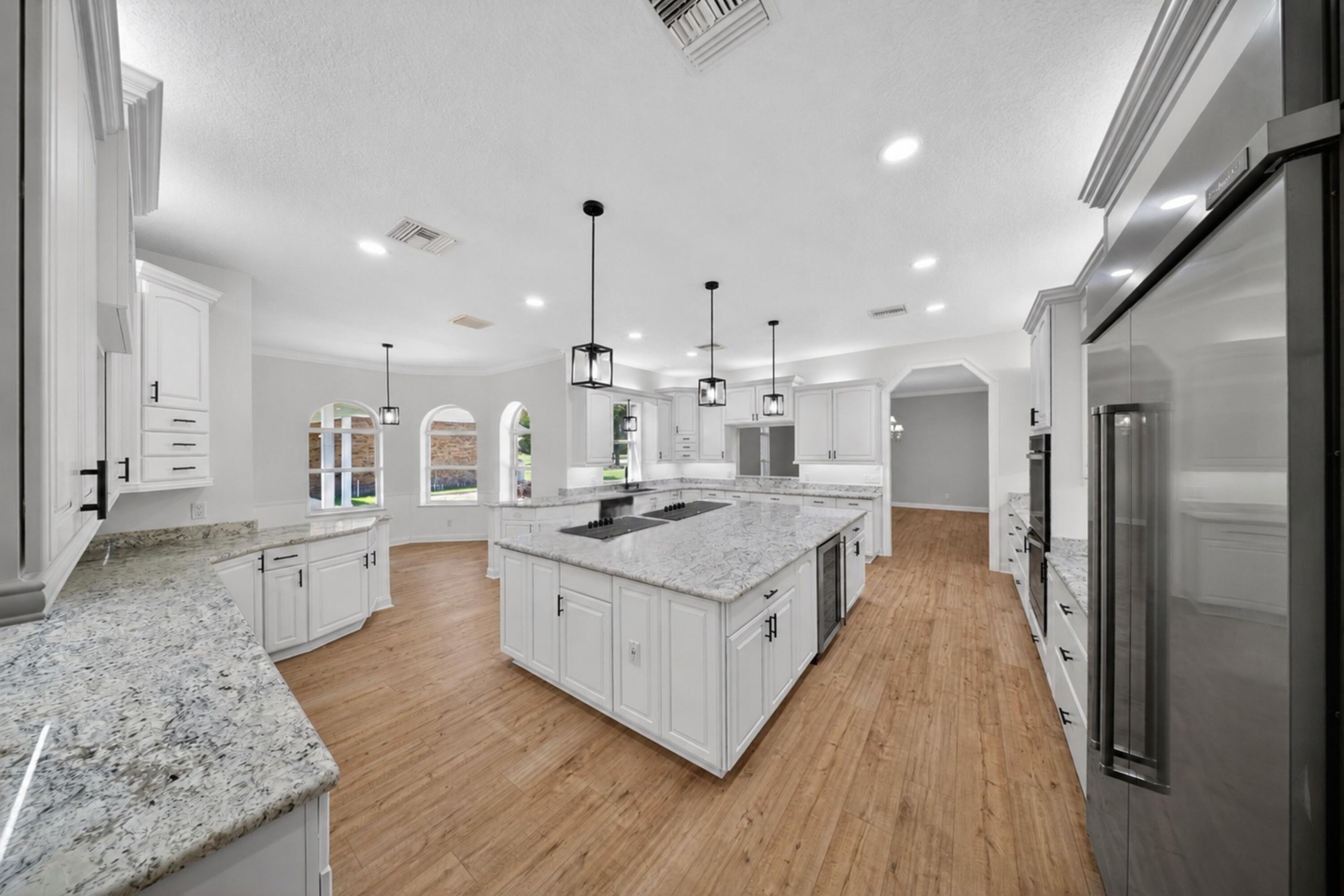 8686 Andrews Avenue Fort Pierce, FL 34945 - Photo 19 of 76 a large kitchen with stainless steel appliances kitchen island granite countertop a large counter top and wooden floors
