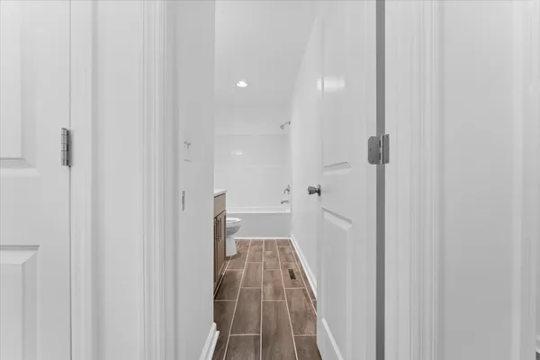 a view of a hallway with wooden floor and a bathroom