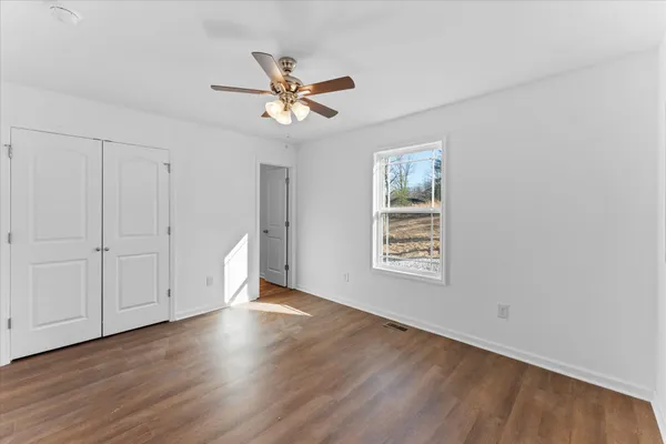 a view of an empty room with a window and wooden floor