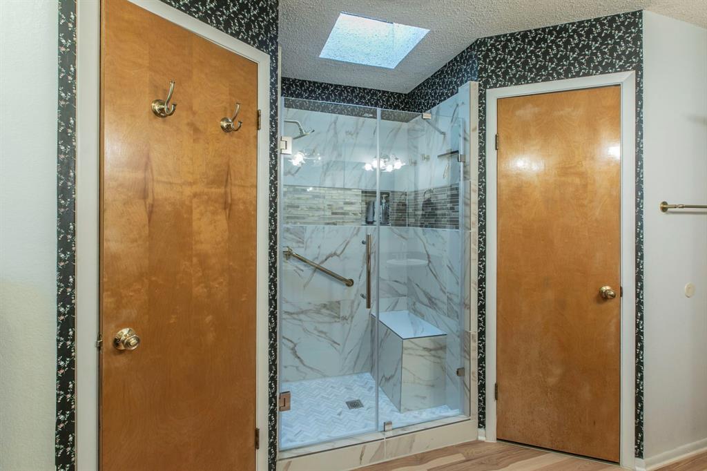 1936 Post Oak Drive Waco, TX 76705 - Photo 19 of 33 Bathroom featuring a skylight, a marble finish shower, wood finished floors, and a textured ceiling