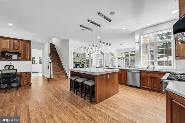 a kitchen with stainless steel appliances granite countertop a stove top oven a refrigerator a sink and dishwasher with wooden floor