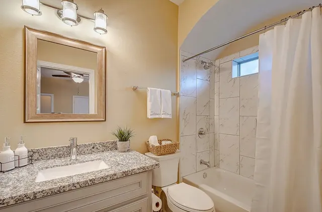 a bathroom with a granite countertop sink toilet and shower