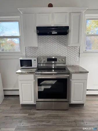 a kitchen with stainless steel appliances a stove a microwave and a hard wood floors