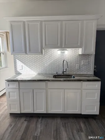 a kitchen with granite countertop white cabinets and a sink