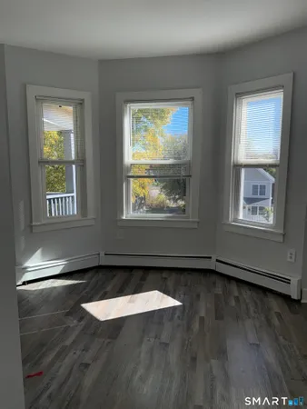 a view of an empty room with wooden floor and a window