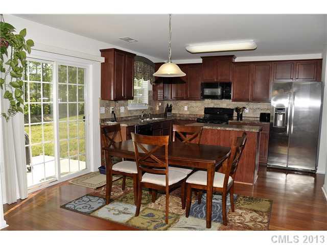 205 Lind Point Lane Monroe, NC 28110 - Photo 9 of 16 a kitchen with stainless steel appliances granite countertop a stove a refrigerator a sink a dining table and chairs with wooden floor