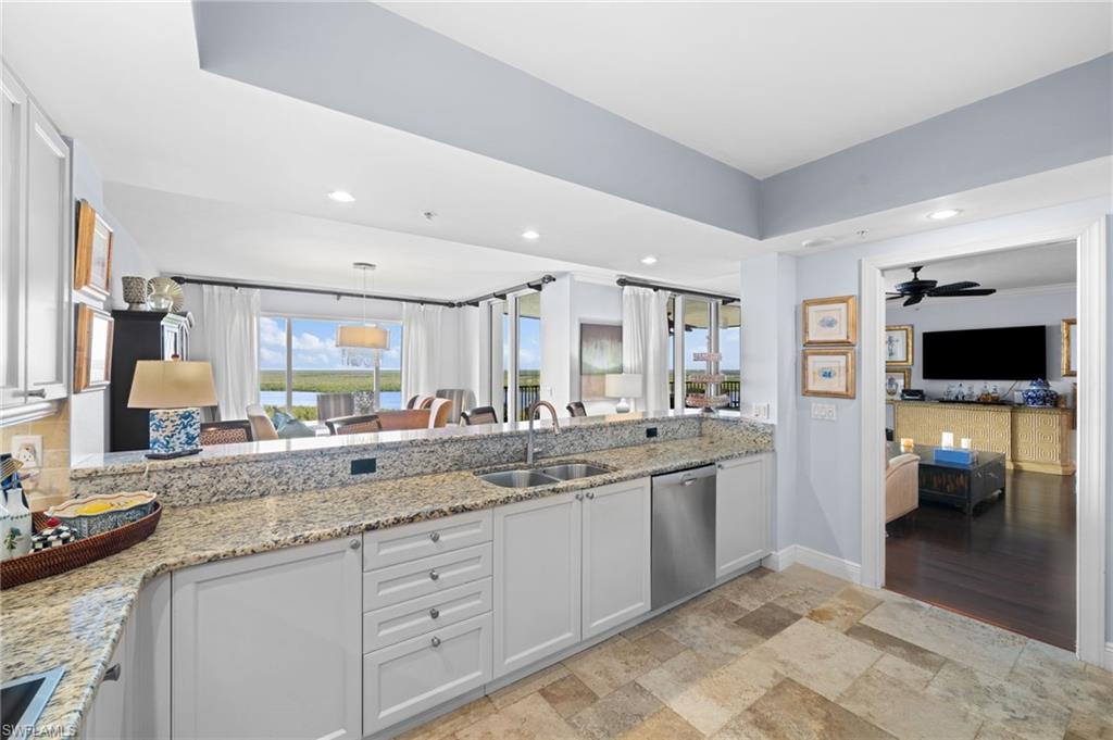 1050 Borghese Lane, Unit 902 Naples, FL 34114 - Photo 19 of 50 Kitchen featuring white cabinets, light stone countertops, sink, ceiling fan, and stainless steel dishwasher