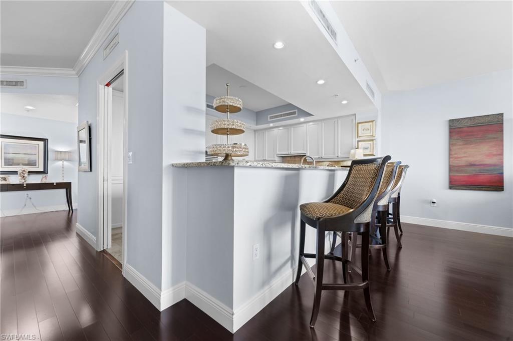 1050 Borghese Lane, Unit 902 Naples, FL 34114 - Photo 21 of 50 Kitchen with dark wood-type flooring, light stone counters, kitchen peninsula, and white cabinets
