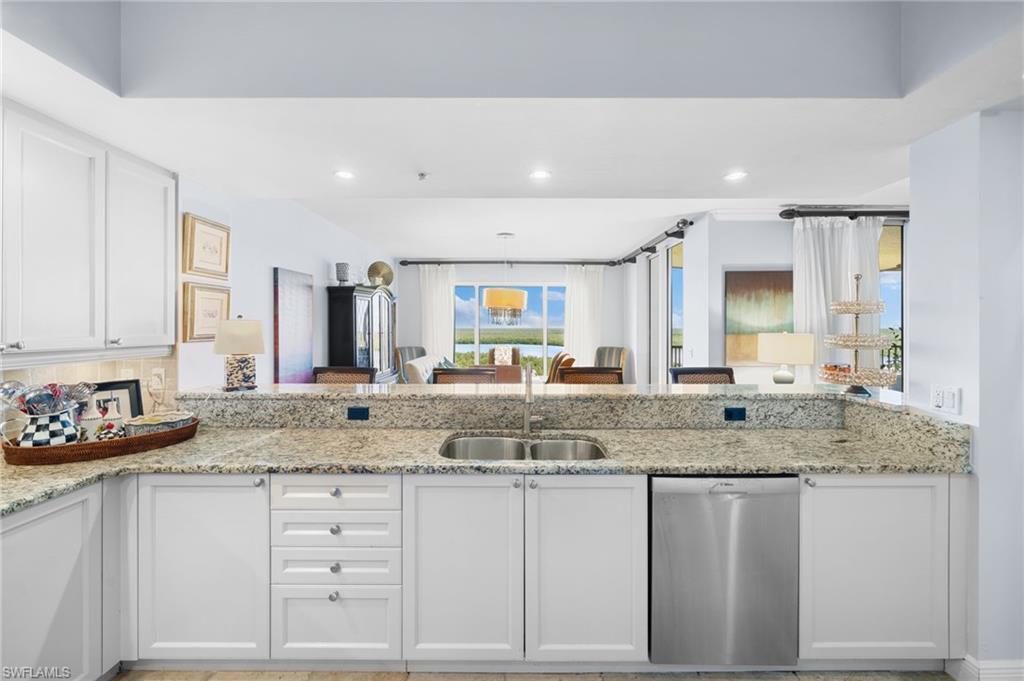 1050 Borghese Lane, Unit 902 Naples, FL 34114 - Photo 23 of 50 Kitchen featuring dishwasher, light stone counters, white cabinetry, sink, and kitchen peninsula