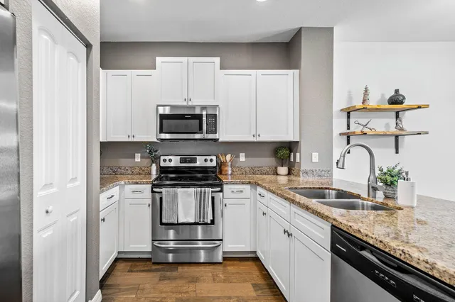 a kitchen with stainless steel appliances granite countertop a sink stove and microwave
