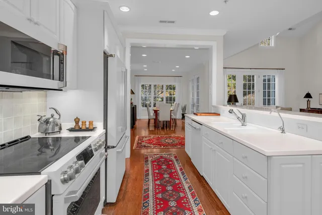 a large white kitchen with sink and stainless steel appliances