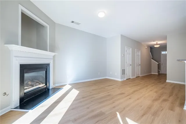 a view of empty room with wooden floor and fireplace