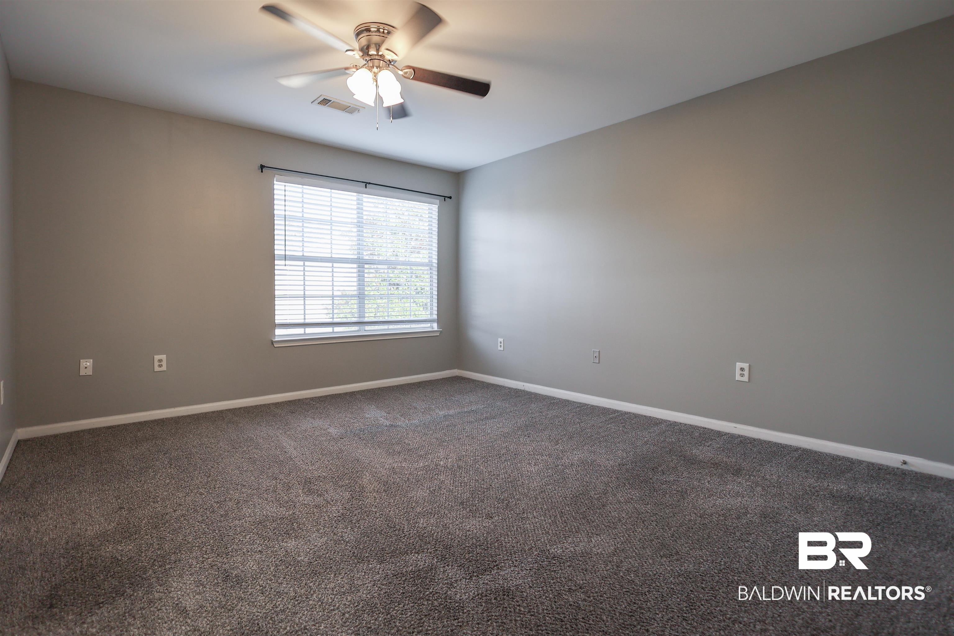 1517 Regency Road, Unit 125 Gulf Shores, AL 36542 - Photo 14 of 26 Empty room featuring dark carpet and ceiling fan