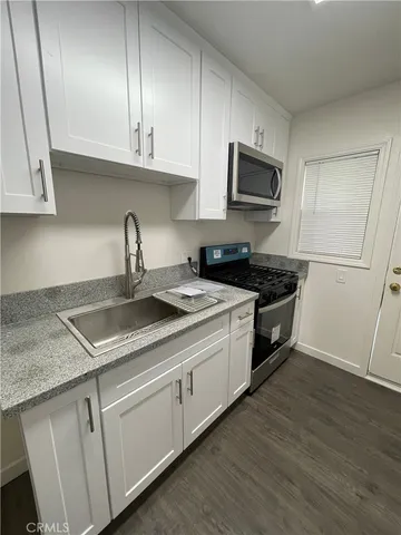 a kitchen with granite countertop a sink a stove and cabinets