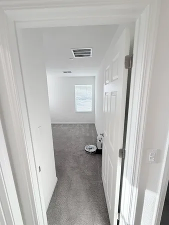 a view of an empty room and a chandelier fan