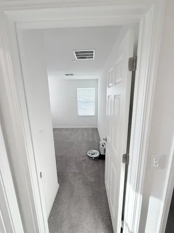a view of an empty room and a chandelier fan