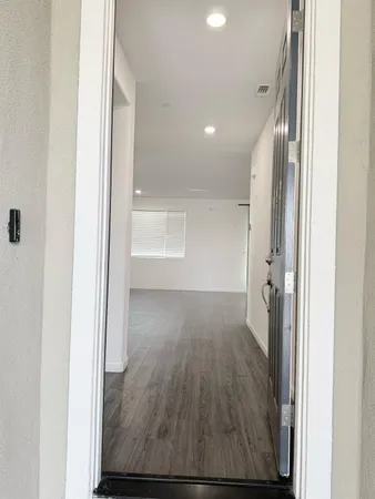 a view of a hallway with wooden floor and a bathroom