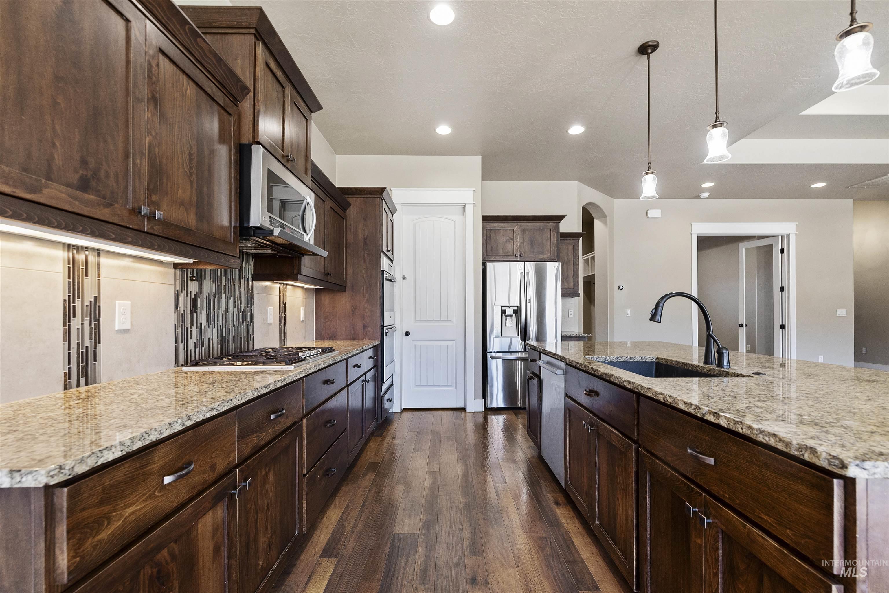 24710 Blessinger Road Star, ID 83669 - Photo 13 of 46 Kitchen featuring an island with sink, light stone countertops, dark wood finished floors, and stainless steel appliances