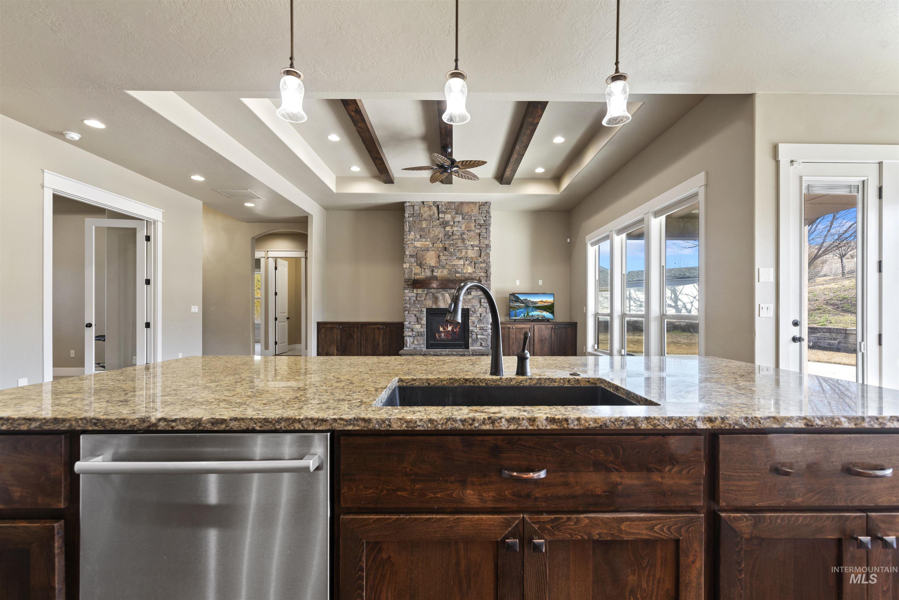 24710 Blessinger Road Star, ID 83669 - Photo 45 of 46 Kitchen with dark wood finish cabinets, dishwasher, a stone fireplace, a raised ceiling, and open floor plan