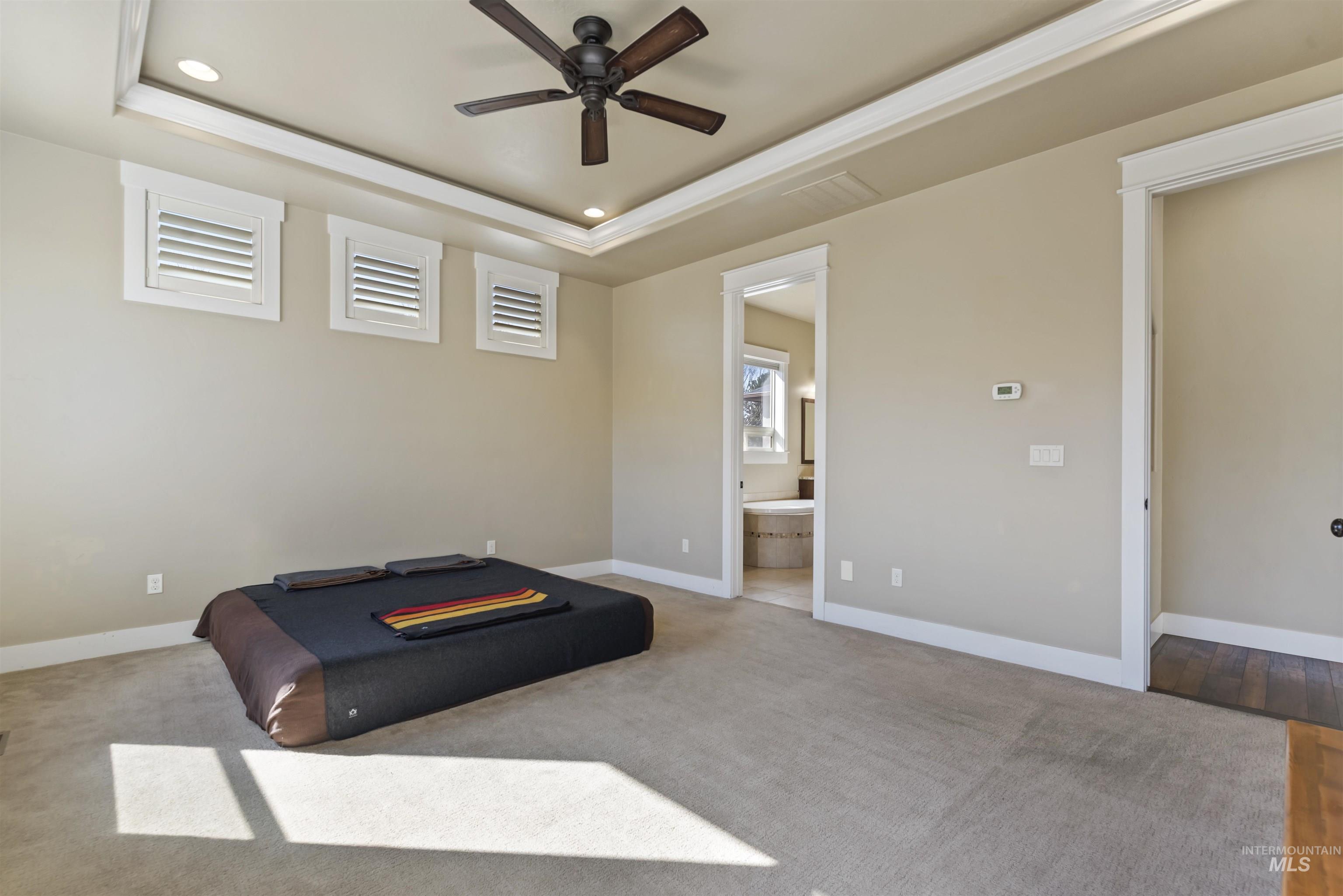 24710 Blessinger Road Star, ID 83669 - Photo 15 of 46 Unfurnished bedroom featuring a ceiling fan, a raised ceiling, connected bathroom, light carpet, and recessed lighting