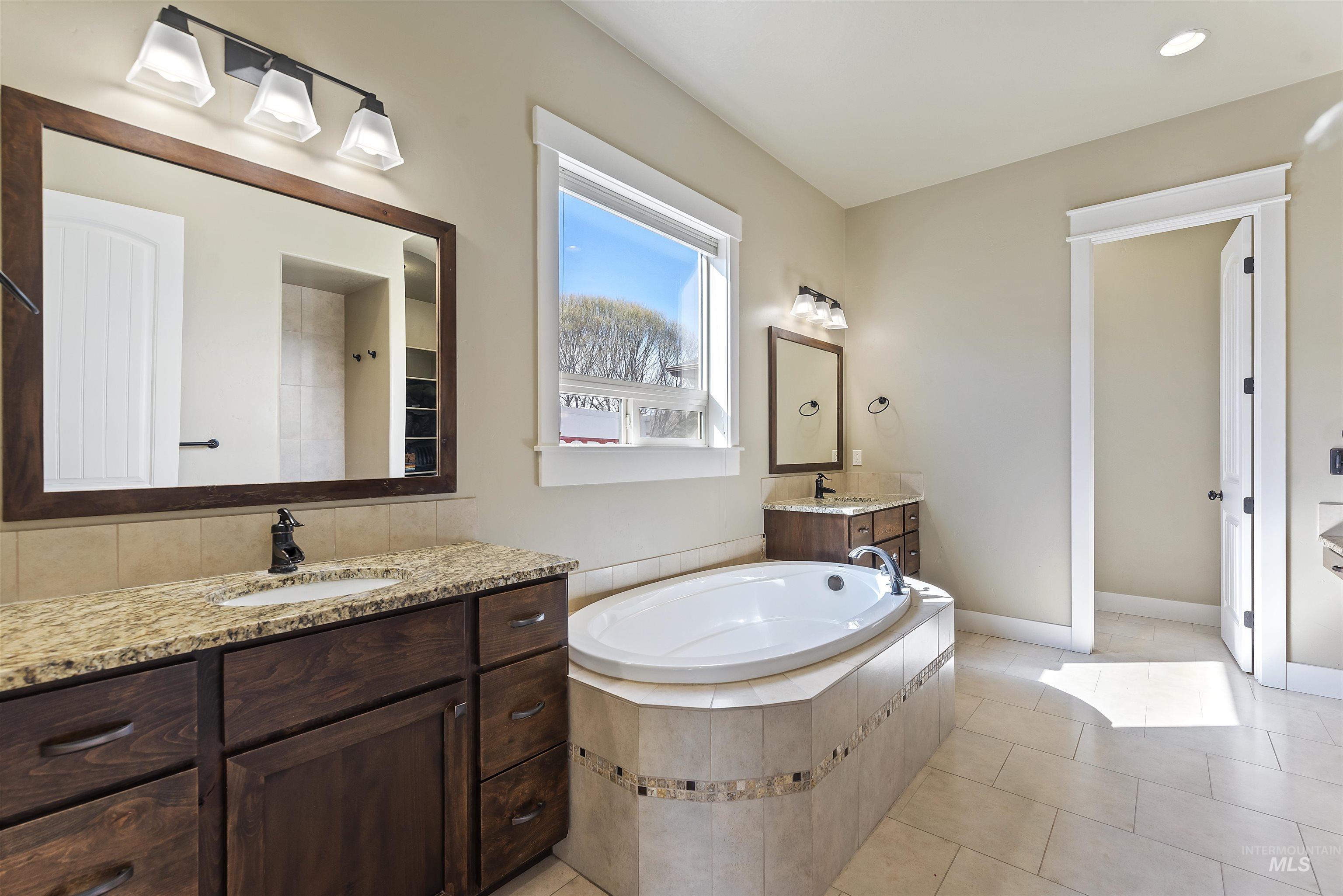 24710 Blessinger Road Star, ID 83669 - Photo 20 of 46 Full bath with two vanities, a bath, and light tile patterned flooring