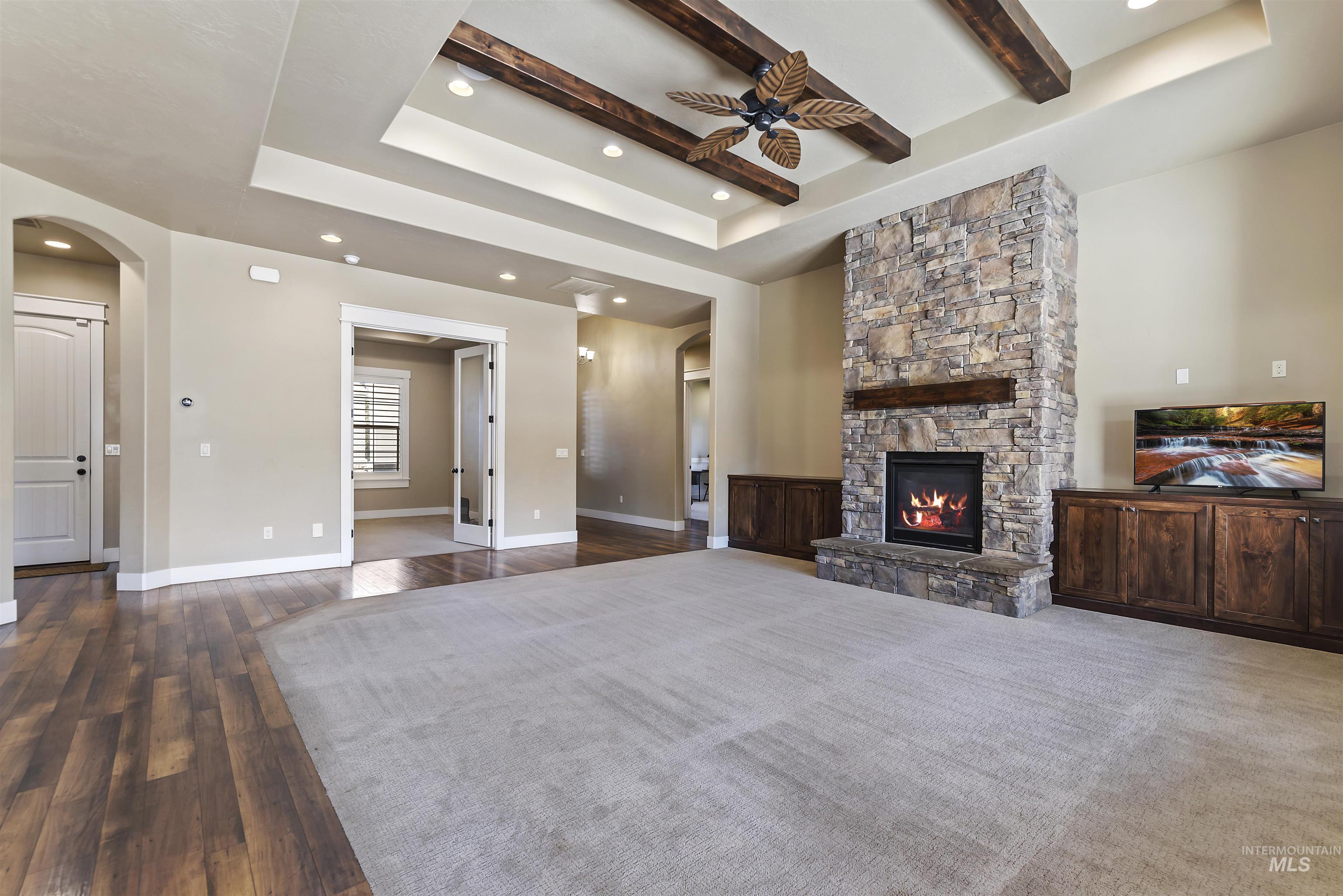 24710 Blessinger Road Star, ID 83669 - Photo 9 of 46 Unfurnished living room with a raised ceiling, beam ceiling, recessed lighting, a fireplace, and dark wood-style floors