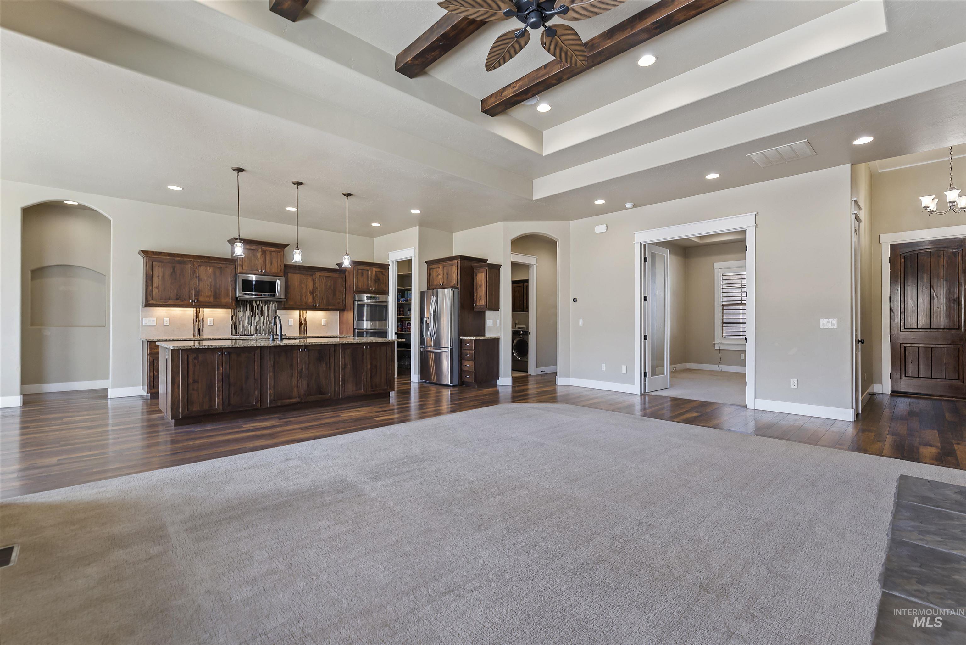 24710 Blessinger Road Star, ID 83669 - Photo 10 of 46 Living room with arched walkways, a raised ceiling, dark wood-style floors, a ceiling fan, and hanging lights