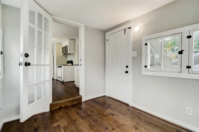 a view of an empty room with wooden floor and a window
