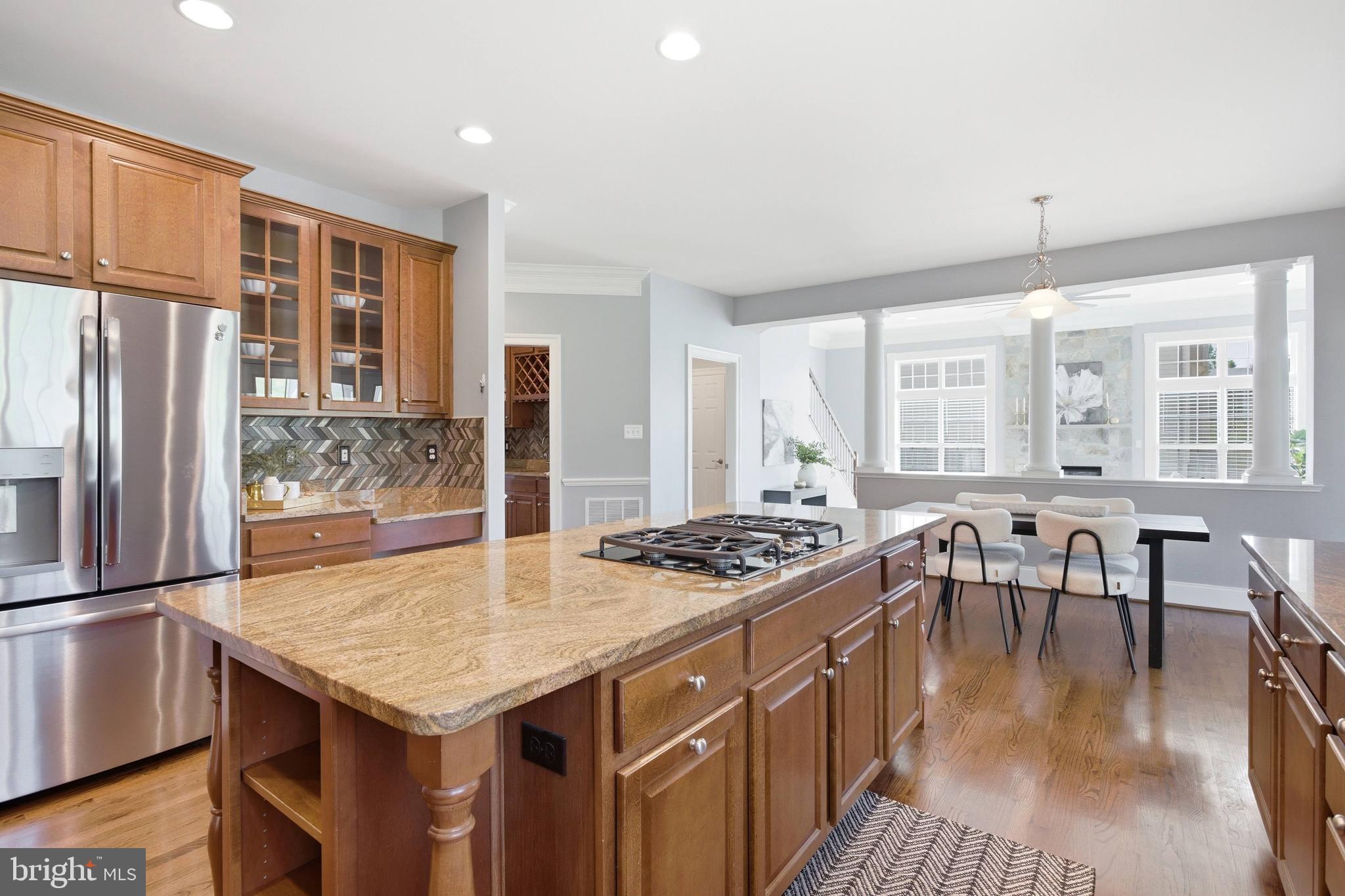 18475 Kerill Road Triangle, VA 22172 - Photo 53 of 99 a kitchen with stainless steel appliances granite countertop a stove a refrigerator a kitchen island a dining table and chairs with wooden floor