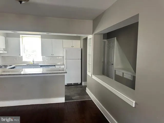 a view of kitchen with granite countertop white cabinets and refrigerator
