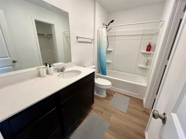 a bathroom with a sink a toilet a mirror and shower