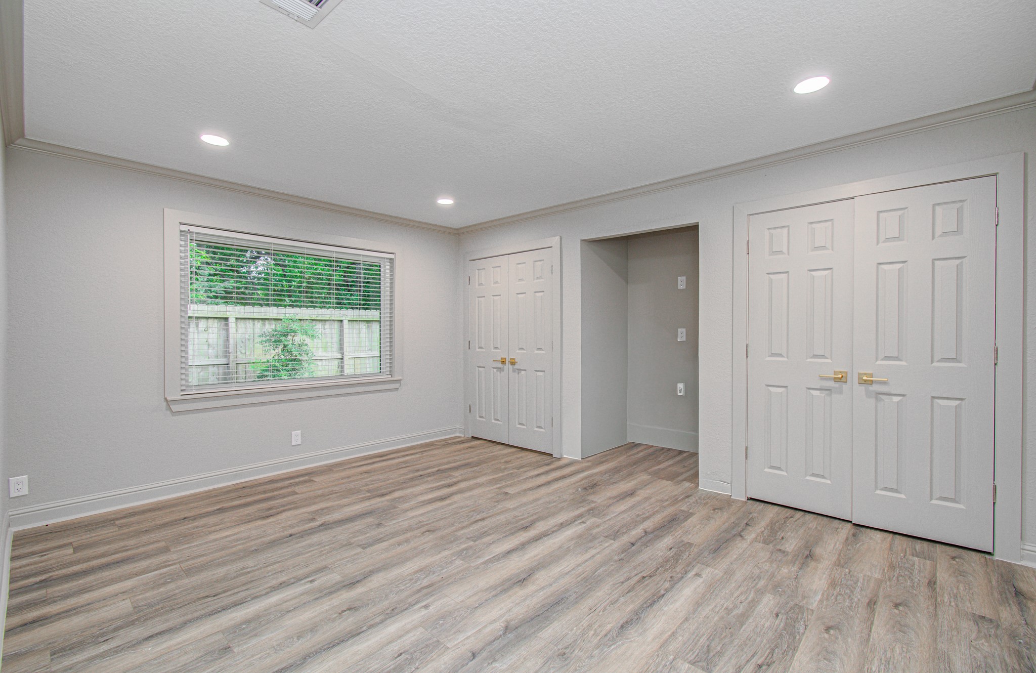 1801 Benbow Way Houston, TX 77080 - Photo 24 of 32 Bright, spacious room with modern wood flooring, neutral walls, and recessed lighting. Features a large window with garden view and ample closet space with double doors.