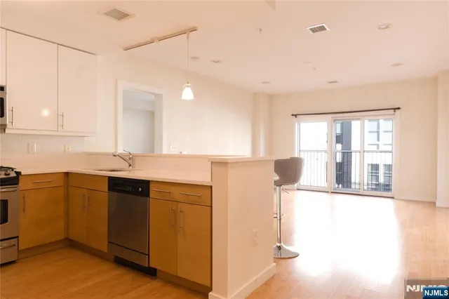 a kitchen with stainless steel appliances granite countertop a sink and cabinets with wooden floor