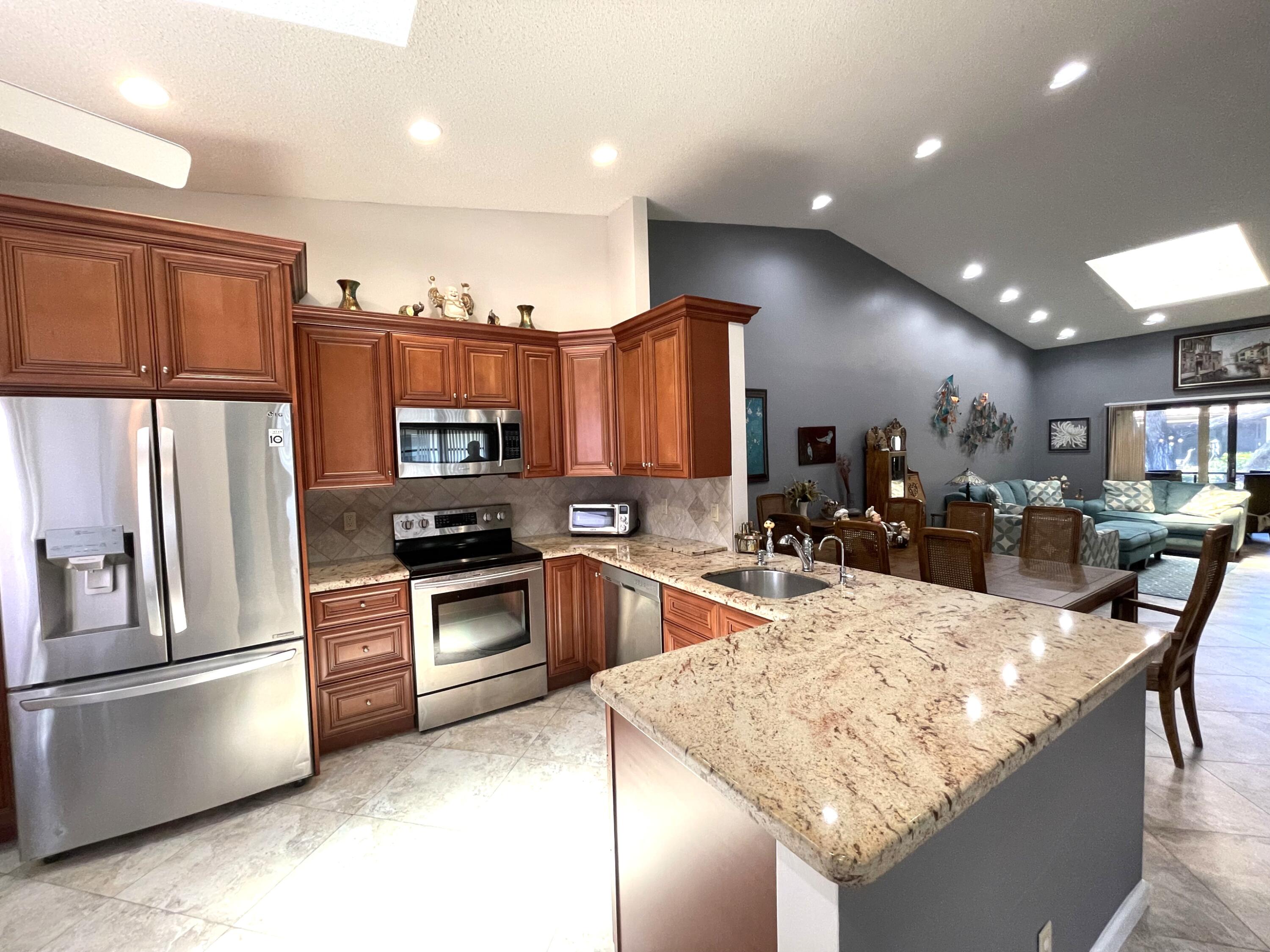 6141 Sunny Pointe Circle, Unit B Delray Beach, FL 33484 - Photo 3 of 62 a kitchen with stainless steel appliances granite countertop a refrigerator stove microwave and sink