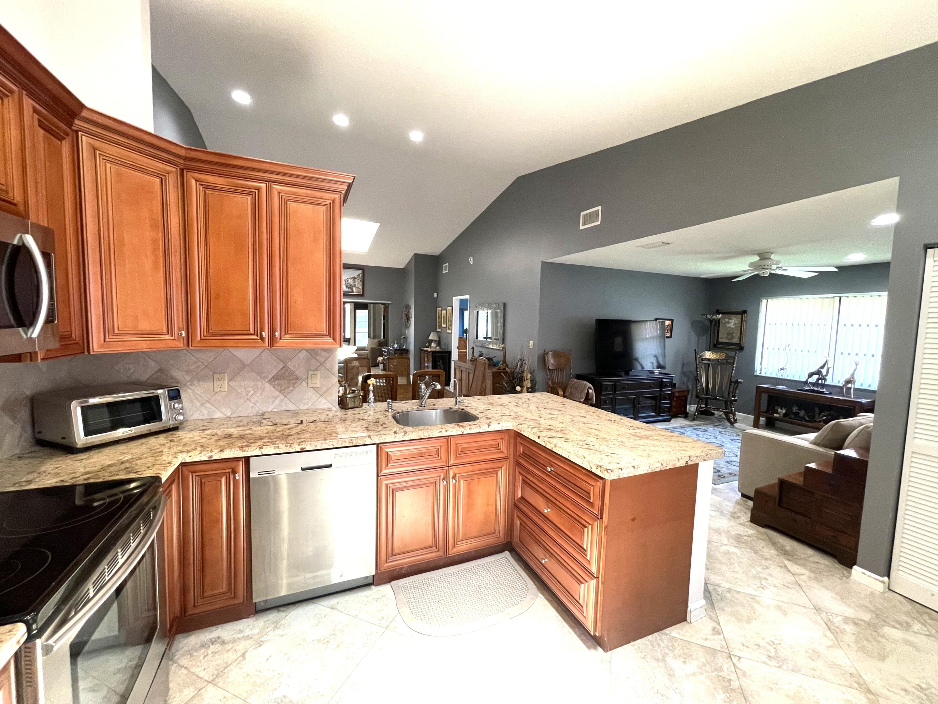 6141 Sunny Pointe Circle, Unit B Delray Beach, FL 33484 - Photo 6 of 62 a kitchen with stainless steel appliances granite countertop a sink and cabinets