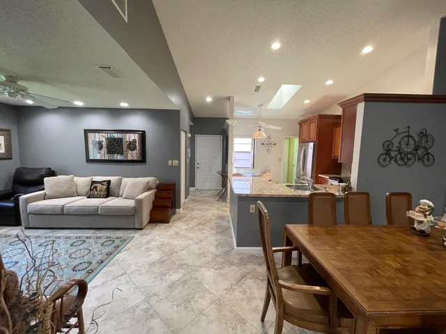 a living room with furniture potted plant and kitchen view
