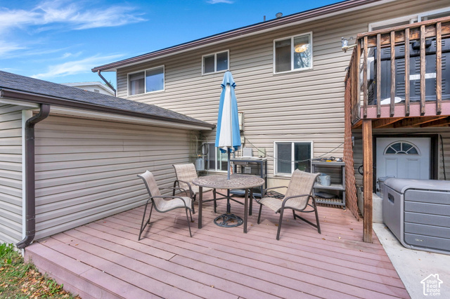 892 Bear Canyon Road Sandy, UT 84094 - Photo 28 of 36 Expansive wood-finish deck with ample space for outdoor furnishing, complemented by a multi-level structure featuring an upper wood-railed deck and a lower-level entry door