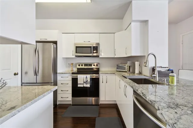 a kitchen with stainless steel appliances granite countertop a sink stove microwave and refrigerator