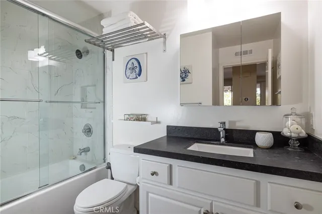 a bathroom with a granite countertop sink a toilet and shower