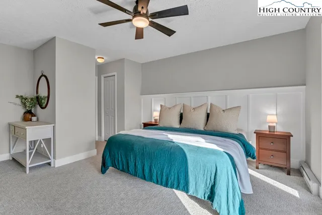 a spacious bedroom with a bed a dresser and a large mirror