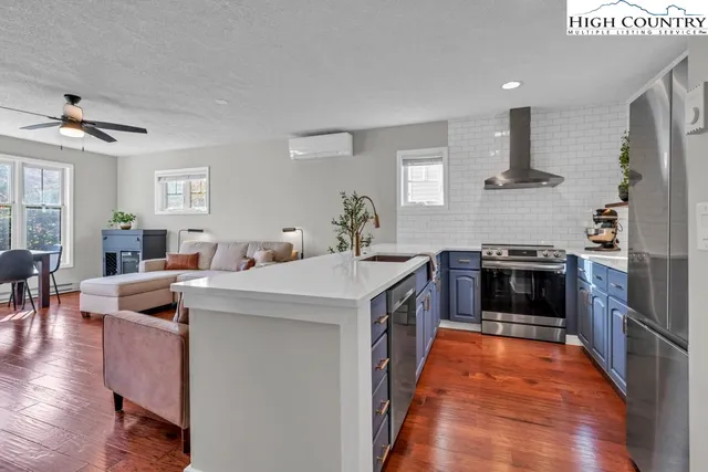 a kitchen with stainless steel appliances a refrigerator sink and wooden floor